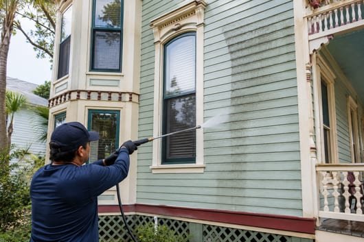 Gentle soft washing of a painted Victorian home's wood siding in Galveston
