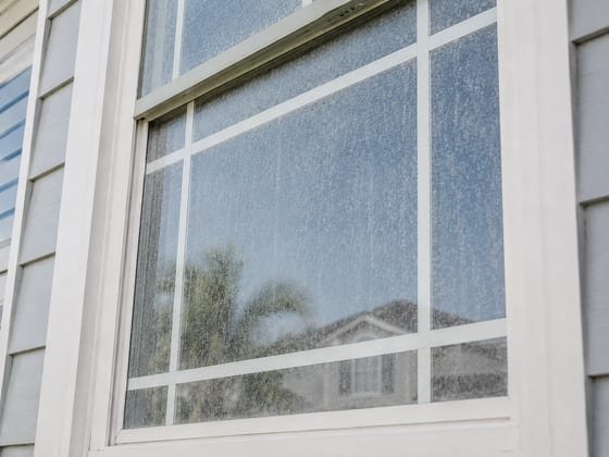 Before: a seawall-facing window clouded with salt film and hard-water spotting